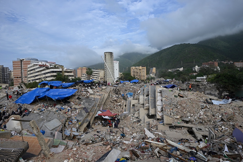 Volunteers and rescue teams still search for bodies amid the rubble of a collapsed building, nearly a month after the 24 June earthquakes (AFP/Getty)