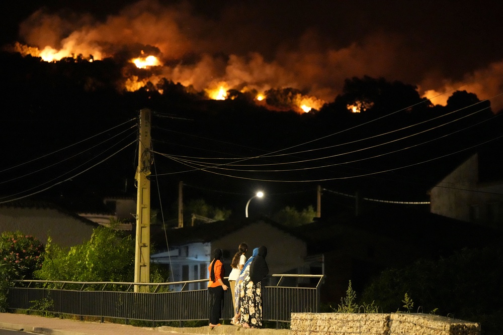 Residents watch the flames on hill crests as firefighters battle a wildfire in Cebreros area, near Avila (AFP/Getty)