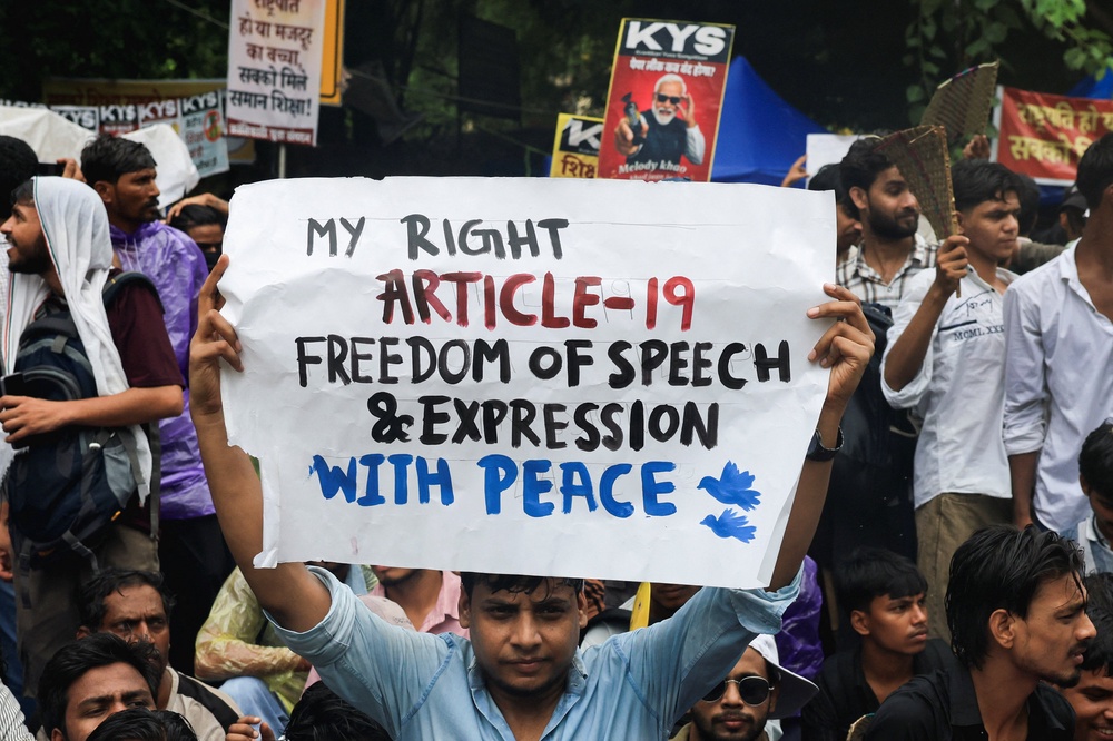 A protester holds a placard during an ongoing protest, days after thousands of protesters marched towards parliament demanding the resignation of Education Minister Dharmendra Pradhan (Reuters)