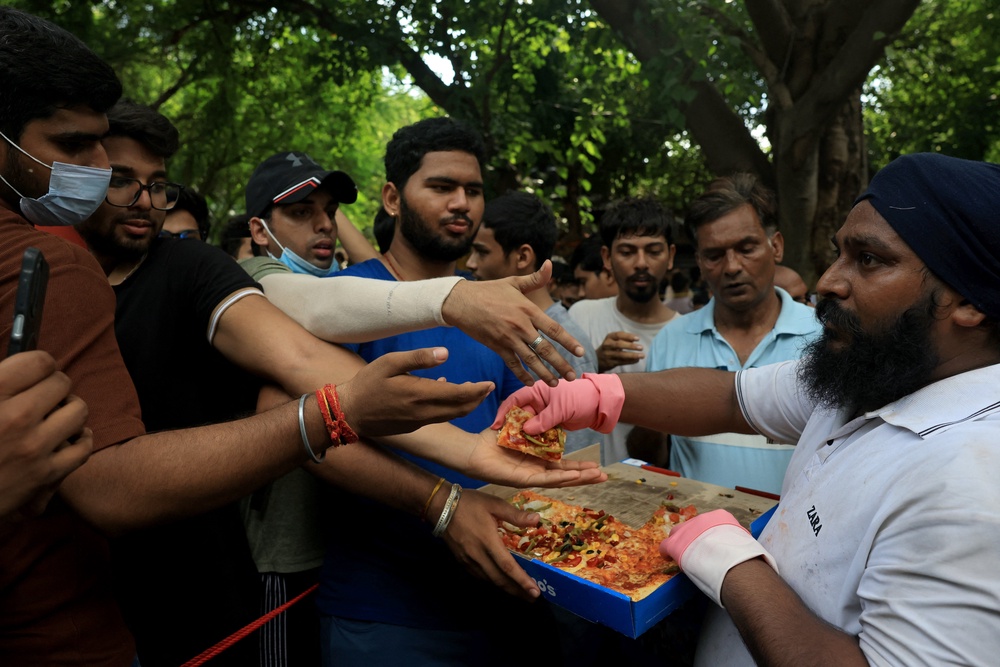 Supporters of India’s Cockroach Janata Party (CJP) queue up for free pizza sent by unknown supporters through food delivery apps (Reuters)