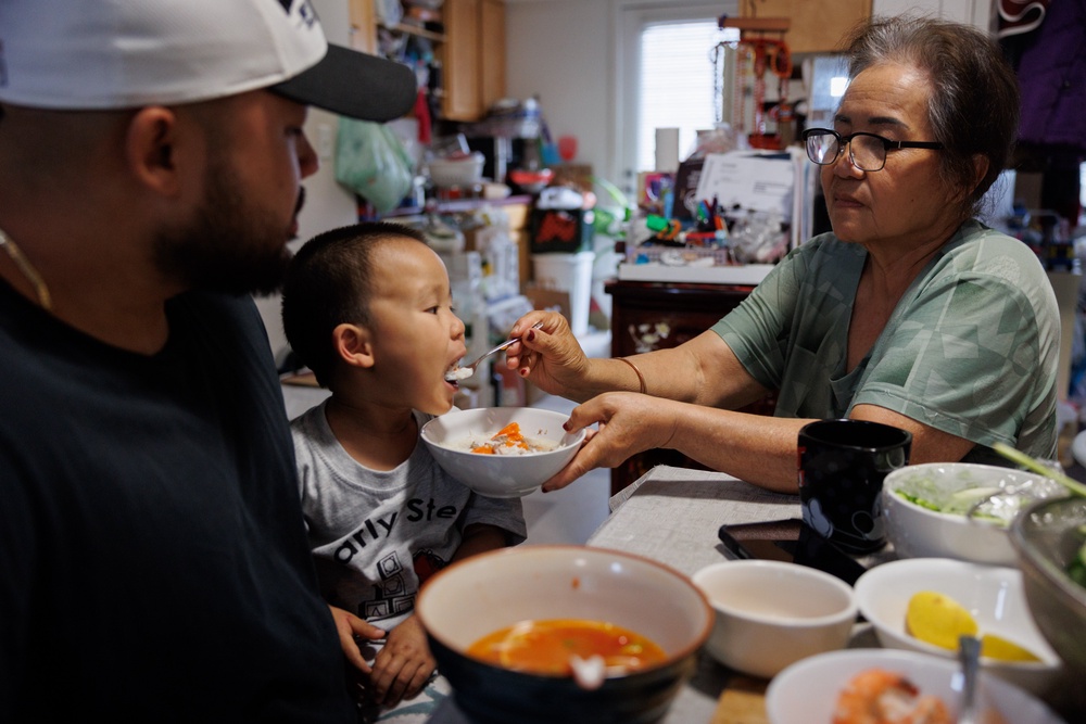 Lien Chang feeds her 2-year-old grandson, Cairo Miu, a bowl of rice next to his dad Jack Chang (AP)