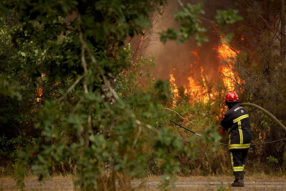 A firefighter pulls a hose on the edge of a burning area in Blagon, west of Bordeaux, on July 26, 2026 as a wildfire has been ravaging the forest north of the Arcachon Basin (Gironde) since July 22. (AFP/Getty)