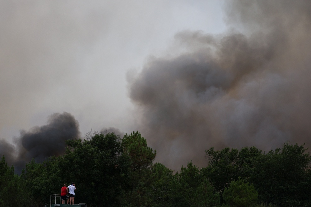 People watch a wildfire from atop a vehicle, amid worsening drought conditions following a heatwave and water shortages across much of the country, in Marcheprime, France (Reuters)
