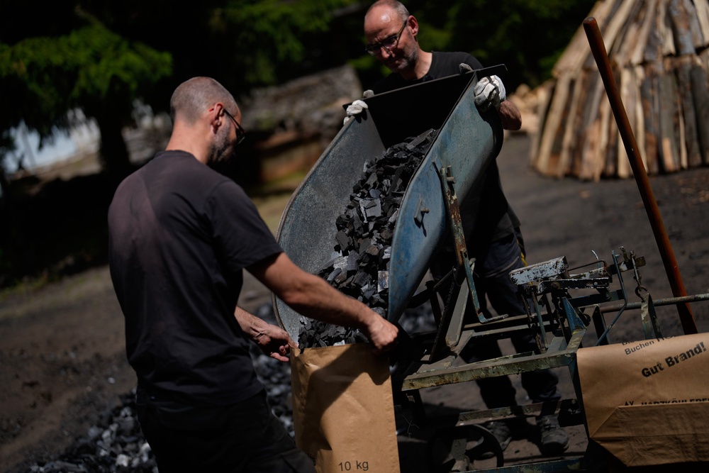 Brothers Immo and Sascha Feldmer put charcoal into paper bags after weighing it at their traditional production site (Copyright 2026 The Associated Press. All rights reserved)
