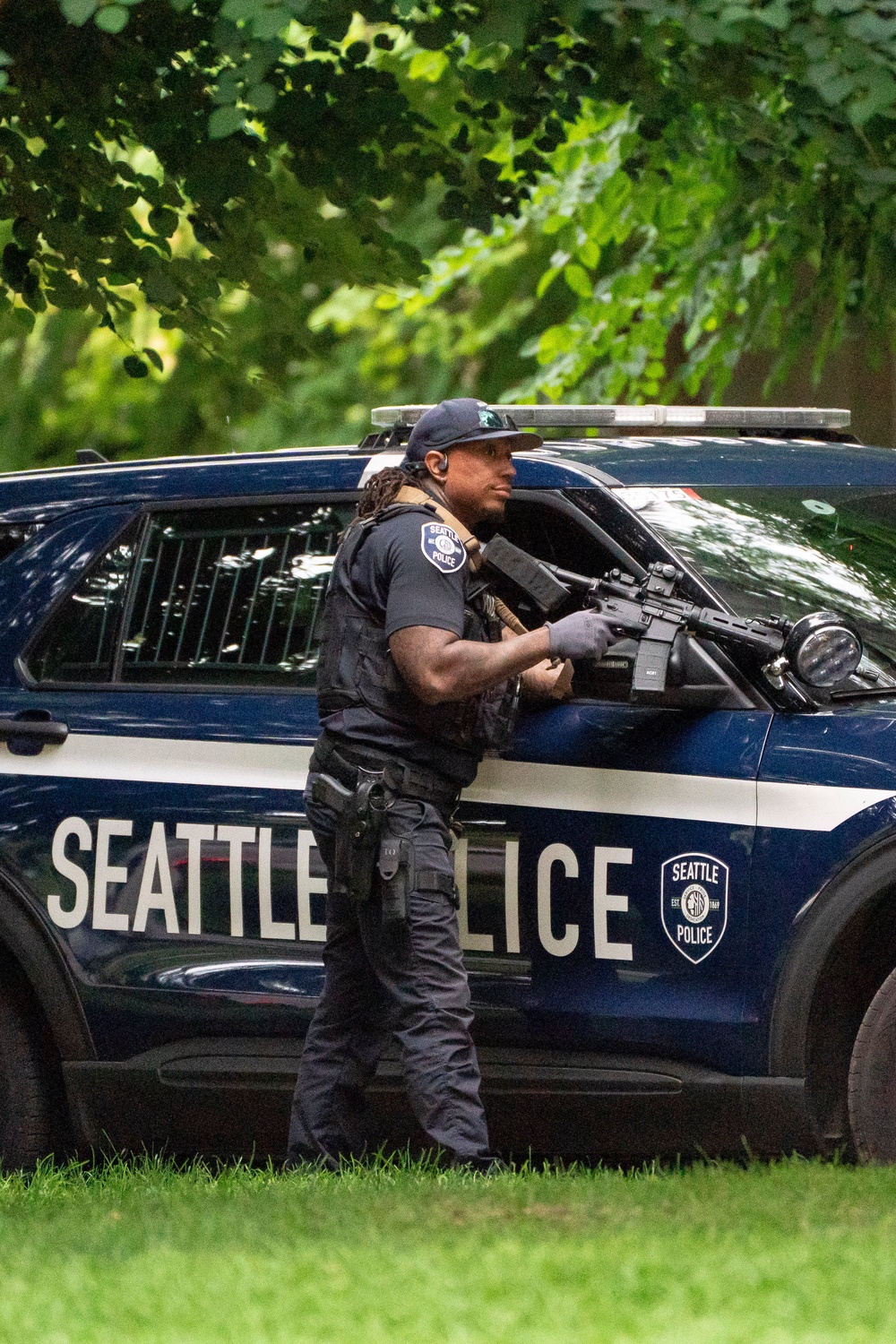 A police officer holds a weapon behind a police vehicle after a mass shooting at the Bite of Seattle food festival on 26 July 2026 in Seattle, Washington (Getty)