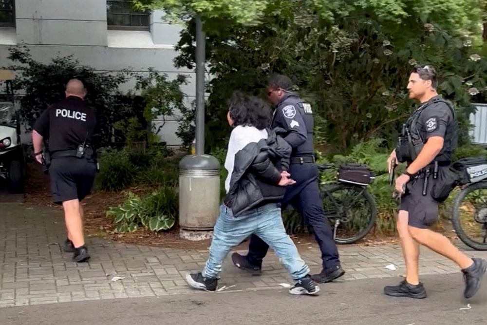A suspect in the shooting is led away by police (Reuters)