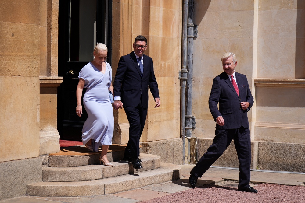 Sir Clive Alderton, right, leaves Buckingham Palace with newly appointed Prime Minister Andy Burnham and his wife Marie-France van Heel on 20 July (Reuters)