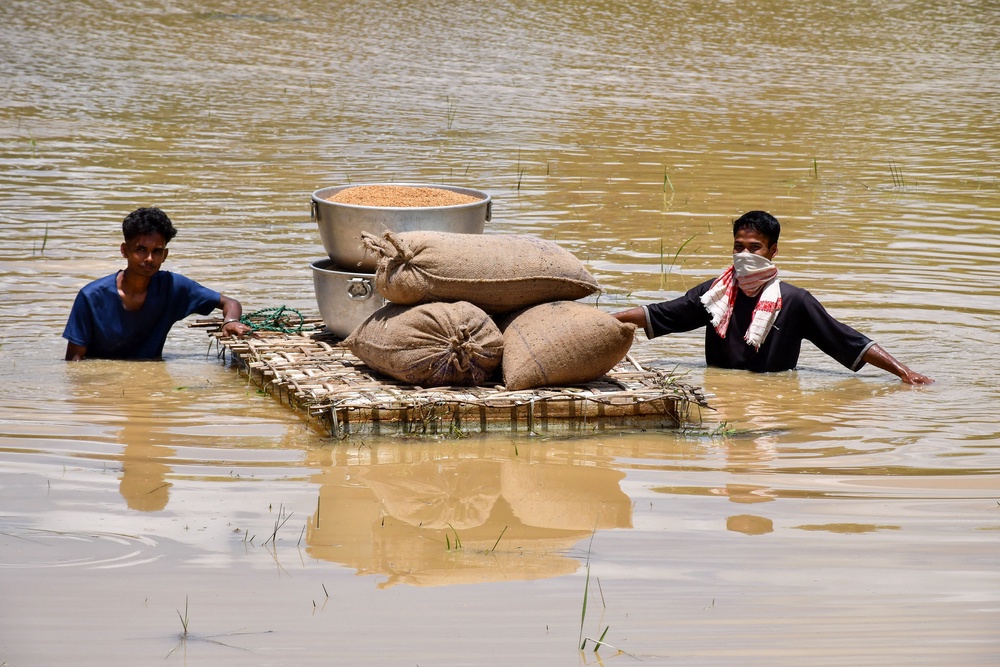 Men carrying food grains on a raft wade through floodwaters following heavy rains in Assam's Jorhat district (AFP/Getty)