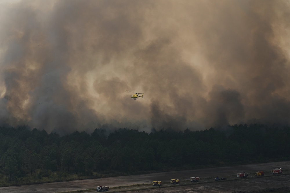 A helicopter flies over firefighting vehicles (AFP/Getty)