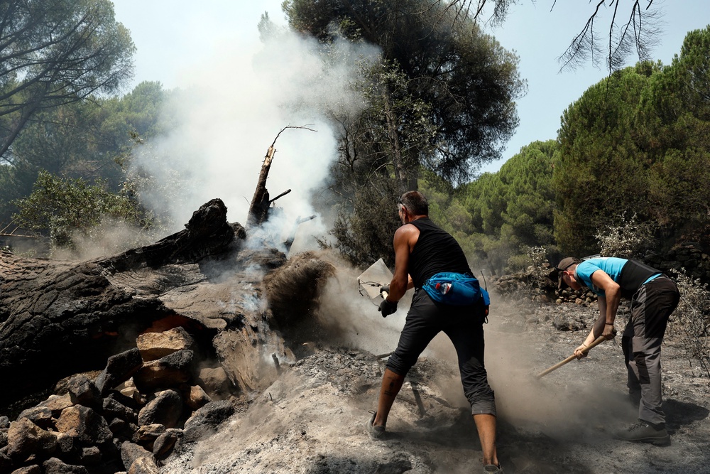 Residents smother embers with dirt to prevent reignition after a fire was brought under control near La Adrada, west of Madrid (AFP/Getty)