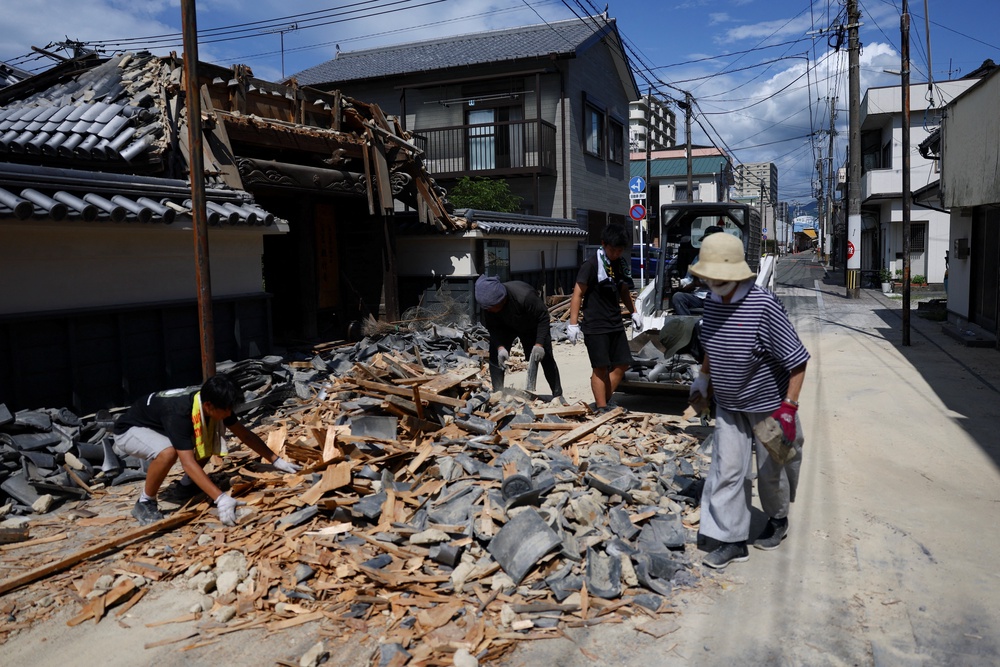 People remove debris from a collapsed gate at a temple due to an earthquake (Reuters)