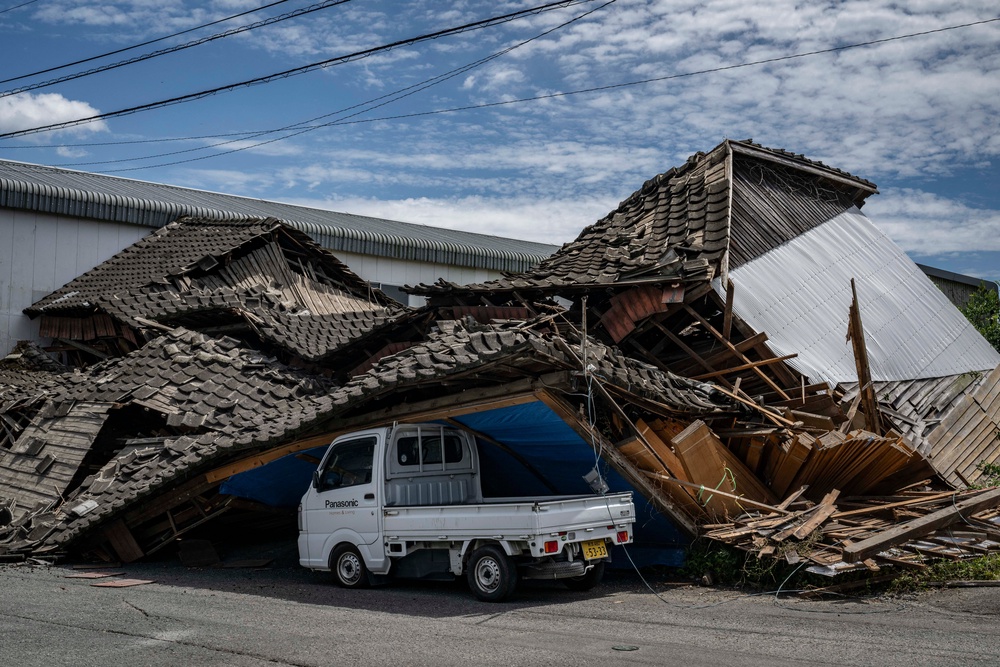 A house is seen collapsed onto a car in Yatsushiro, Kumamoto prefecture (AFP/Getty)
