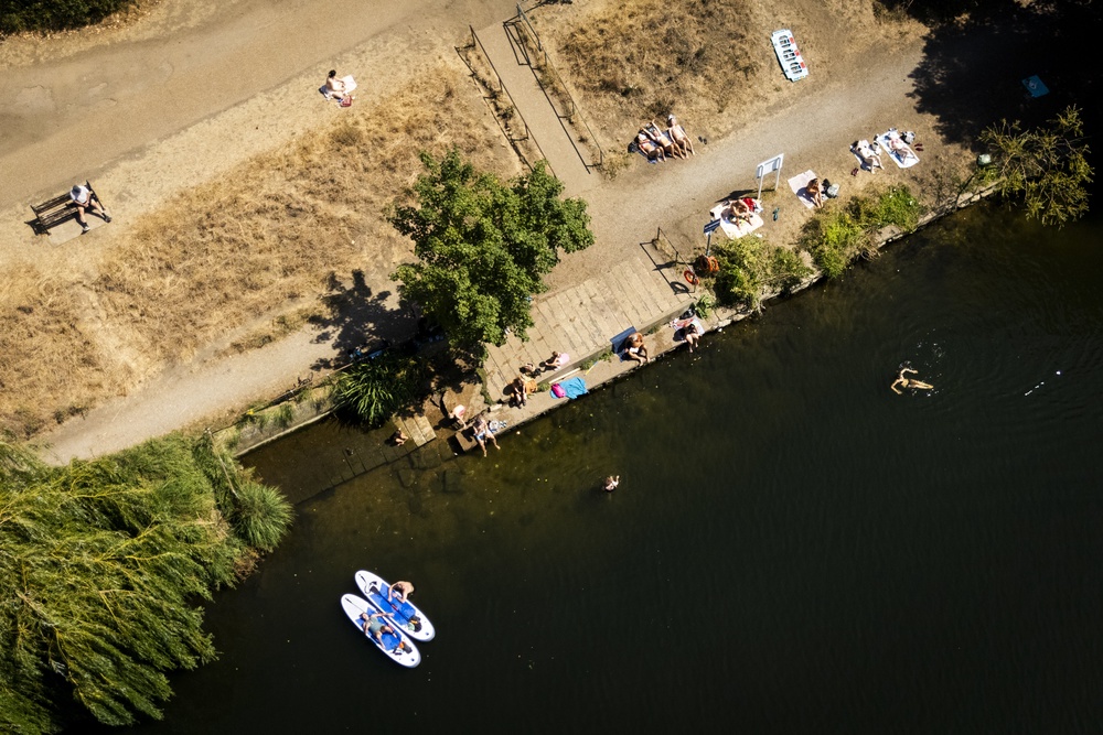 People sunbathing and swimming in the water at the Thames at Ham (PA)