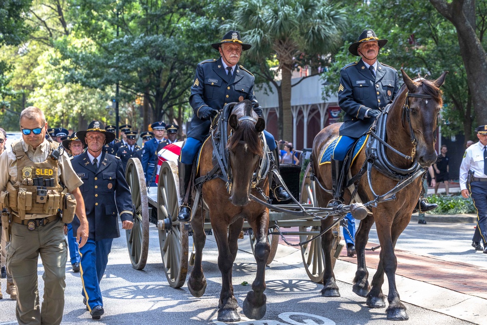 A horse-drawn caisson carrying his casket paused in front of a dozen law enforcement officers for a flyover by four military jets, and then proceeded to the church (Grant Baldwin/Getty Images)