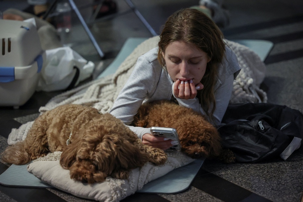A woman takes shelter with her dogs inside an overcrowded metro station during a Russian missile and drone strike (Reuters)