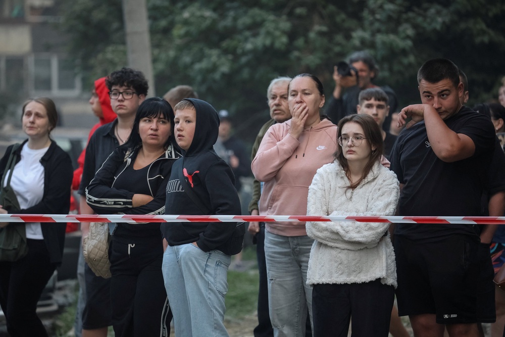Residents stand at the site of an apartment building hit by a Russian missile strike, amid Russia's attack on Ukraine, in Lviv (Reuters)