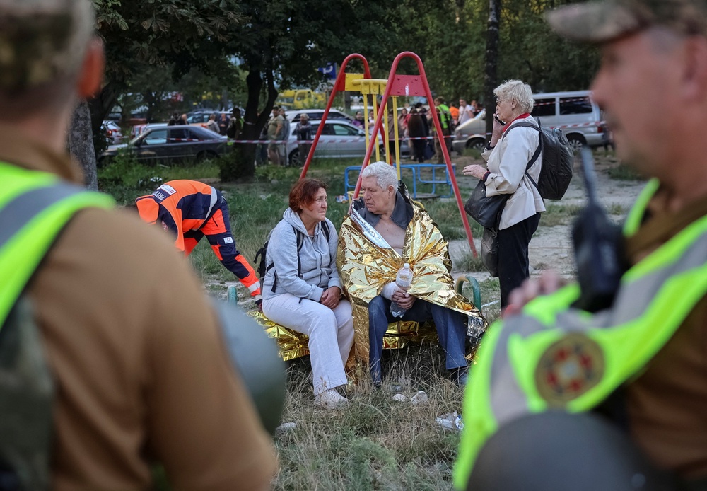 Residents sit at the site of an apartment building hit by a Russian missile strike (Reuters)