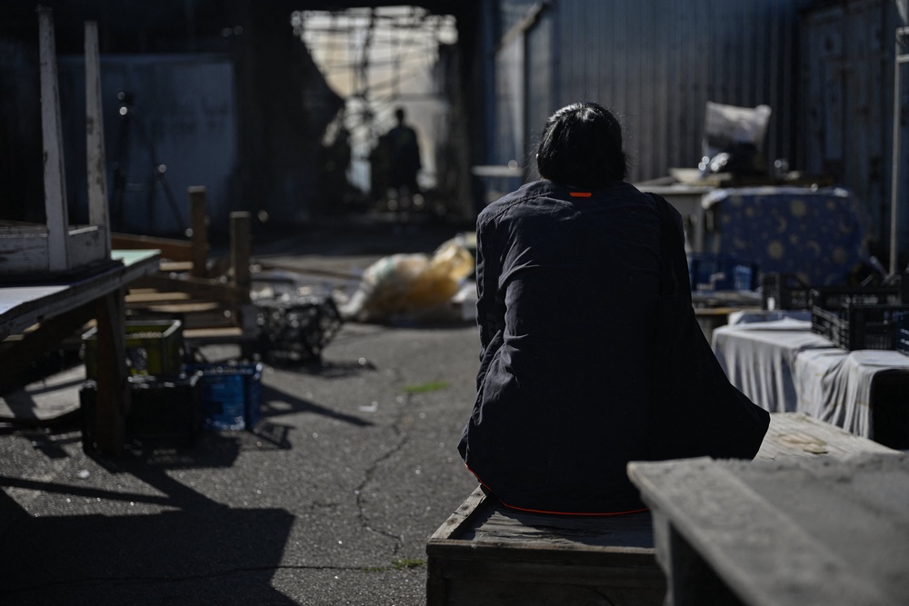 A Ukrainian vendor sits amidst the damage caused by a strike on a market in Kyiv (AFP/Getty)