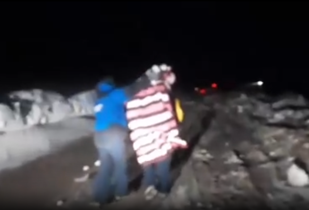 A tourist wrapped in blankets is rescued from their vehicle (Reuters)