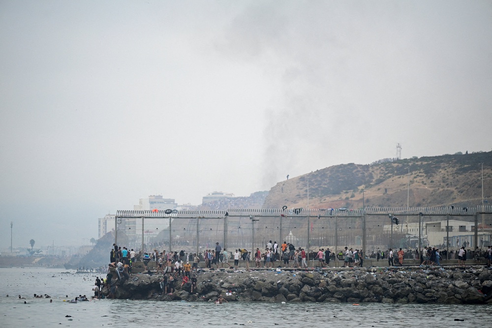 Migrants from Morocco gather by the border fence as they cross the Spanish border, swimming through the sea, as seen from Ceuta, Spain, July 31, 2026. (REUTERS/Fabian Bimmer) (Reuters)