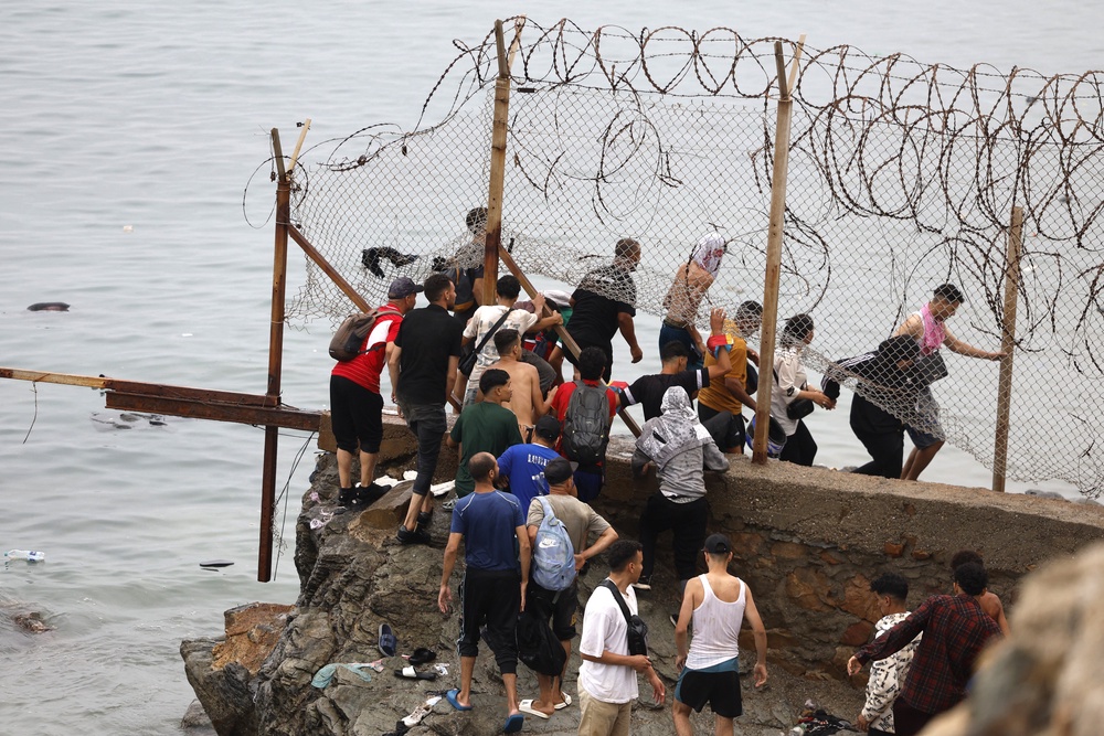 Spain estimates that about 69,500 migrants have returned to Morocco over the past four days, exceeding initial estimates of around 50,000 arrivals in Ceuta on Thursday (File - people cross the border on 31 July) (AFP/Getty)