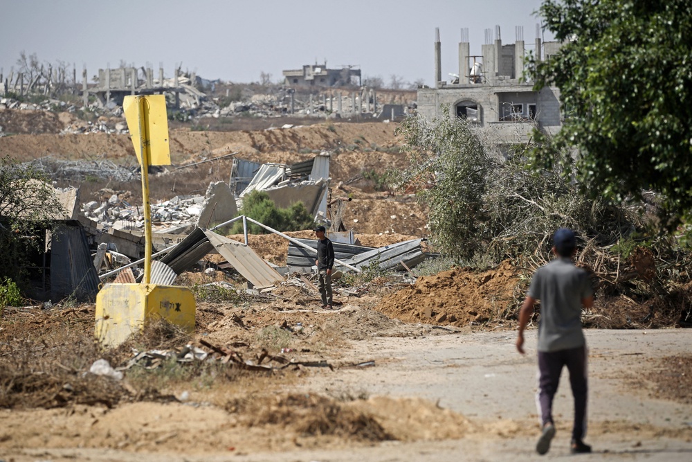 Palestinians walk past a concrete block marking the 'Yellow Line' drawn by the Israeli military (AFP/Getty)