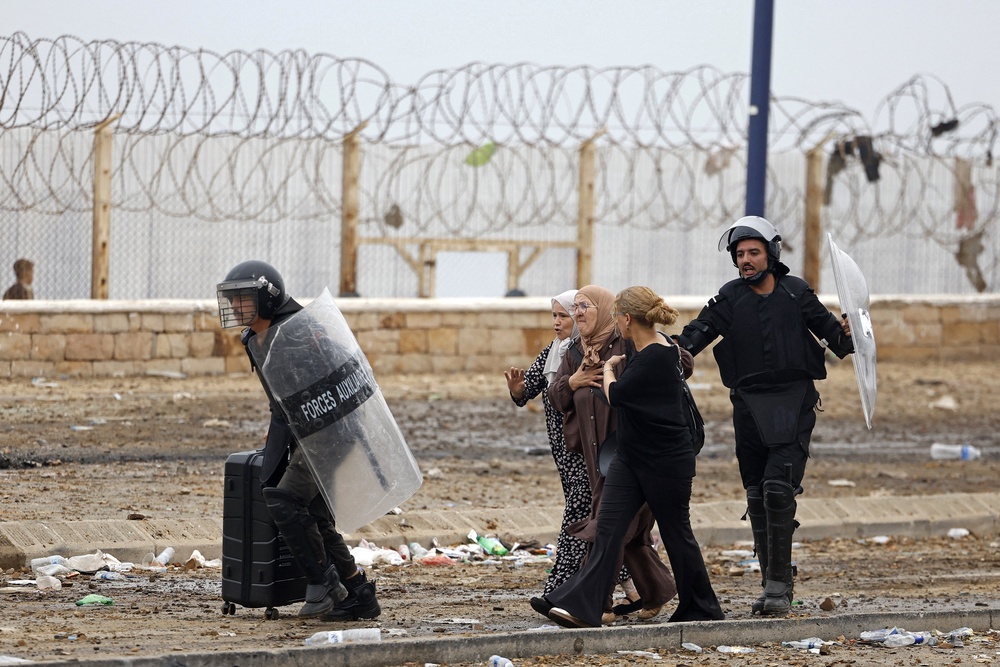 Members of Moroccan security forces escort women from the site of clashes near Fnideq, on the Morocco-Spain border, on July 31, 2026. (Photo by Abdel Majid BZIOUAT / AFP via Getty Images) (AFP/Getty)