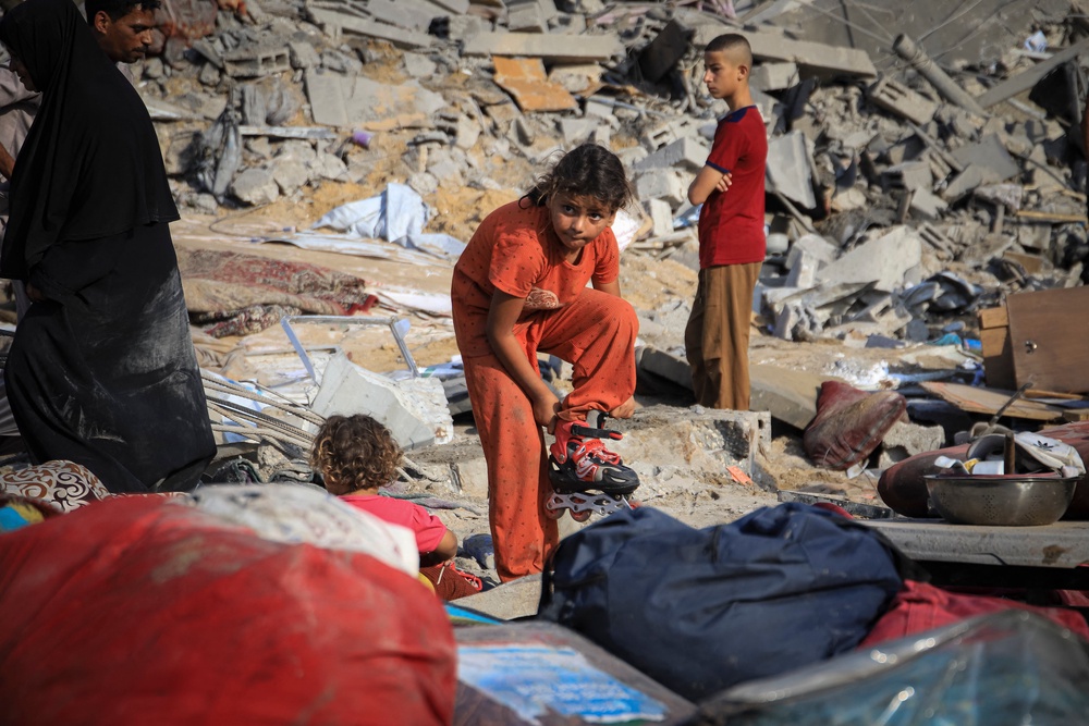 Palestinian children search among clothing and household belongings scattered across the rubble after an Israeli airstrike in the Al-Nasr (AFP/Getty)