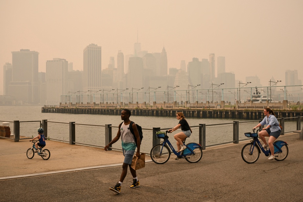 People walk and bike in New York City earlier this month as dangerous Canadian wildfire smoke fills the skies. Wildfire smoke has been linked to developing cancer (AFP/Getty)