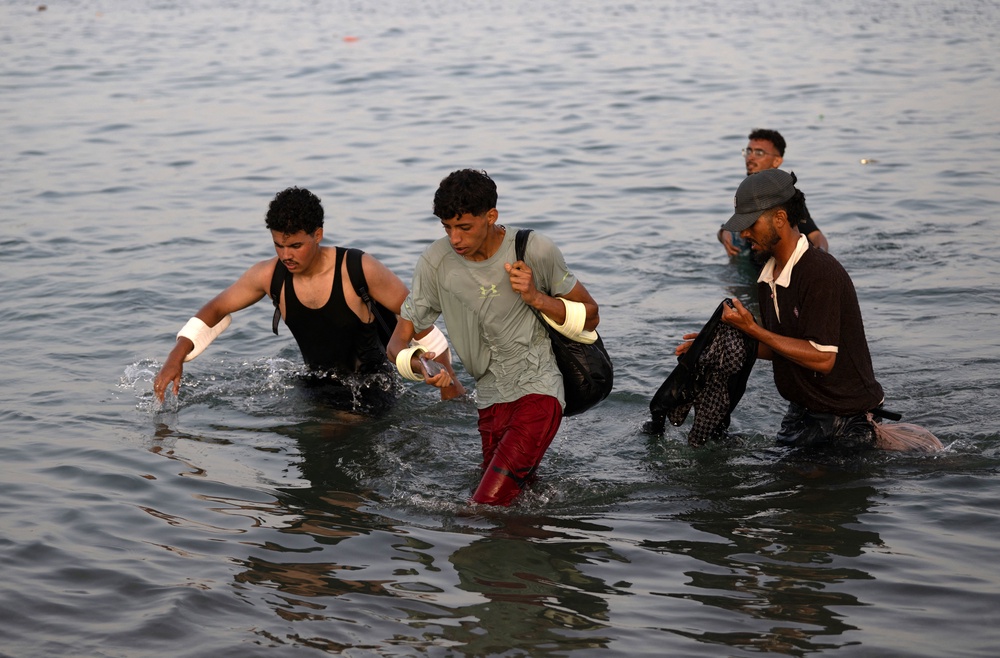 Migrants wade through the water near the border with Morocco (AFP/Getty)
