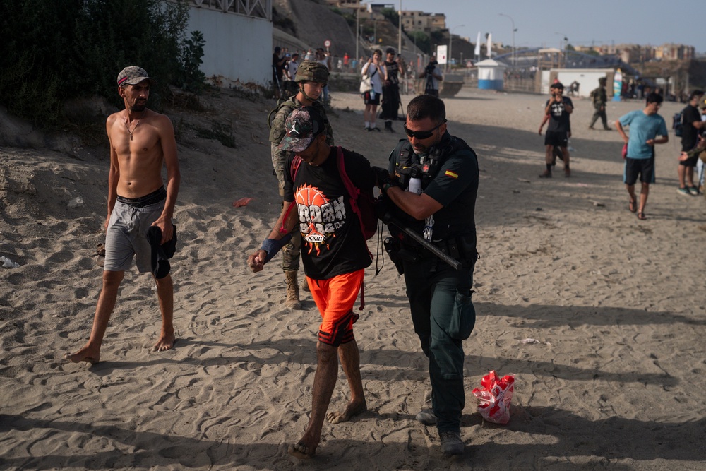 A member of the Guardia Civil USECIC restrains a migrant after arriving on Tarajal beach after crossing the border between Spain and Morocco (Getty)