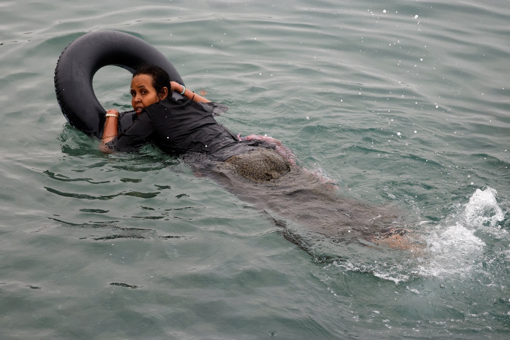 Filiss, 32, from Somalia uses a float to cross into Ceuta by sea, at El Tarajal beach, amid mass crossings of migrants from Morocco into Spanish territory (Reuters)