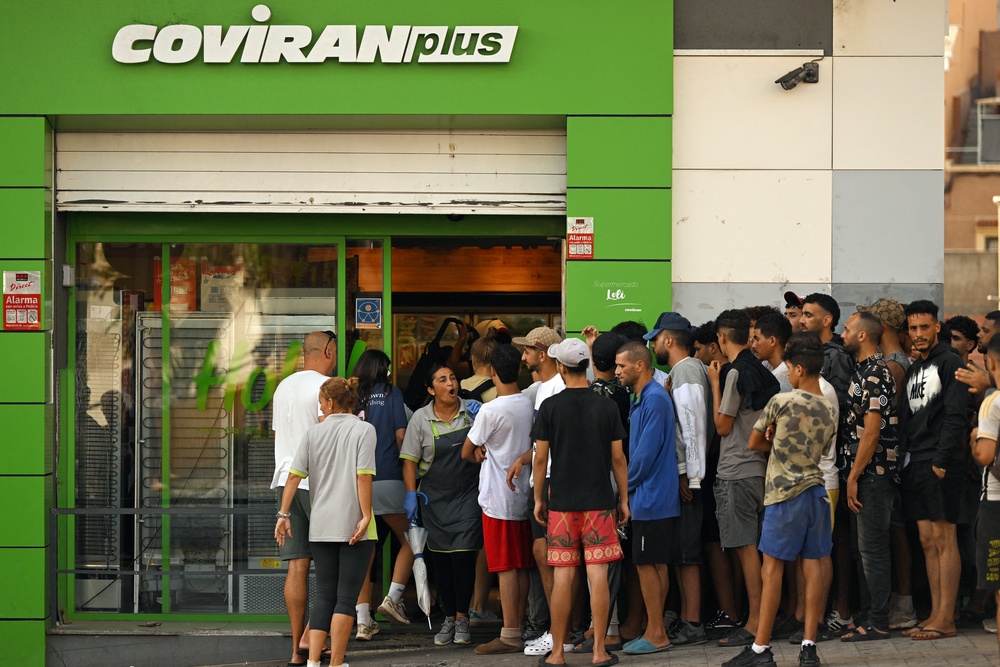Supermarket employees (L) try to turn away a group of migrants attempting to enter a store in Ceuta (AFP/Getty)
