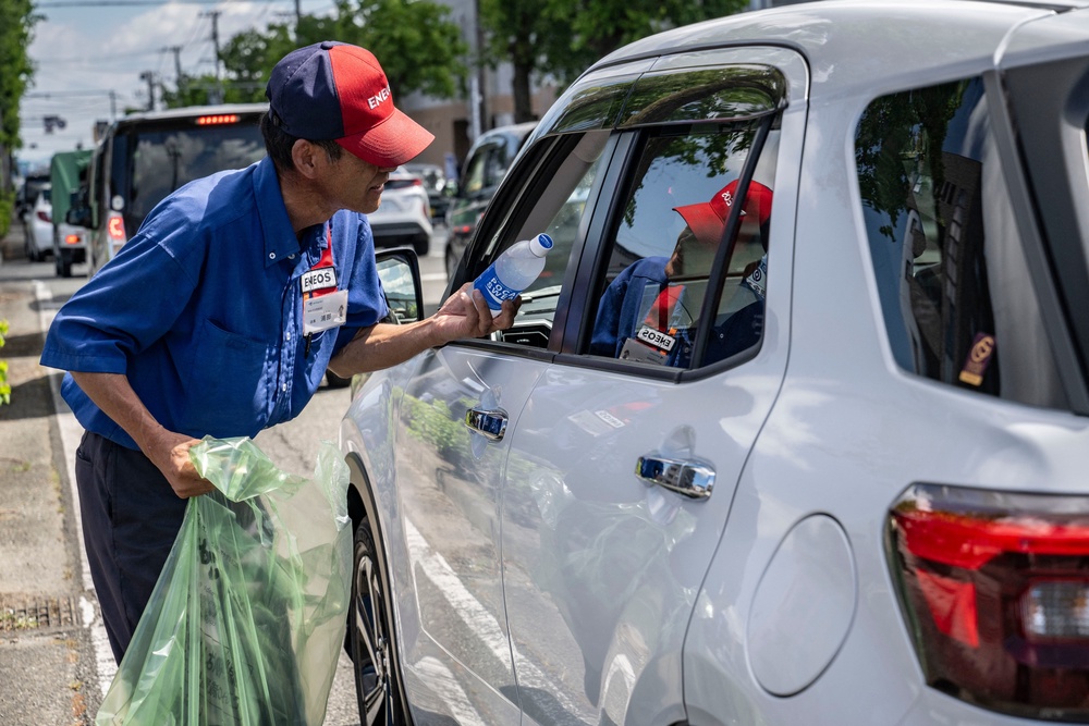 A gas station employee distributes drinks to drivers waiting in line for fuel following the the July 28 earthquake, in Yatsushiro, Kumamoto prefecture (AFP/Getty)