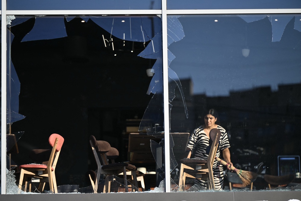 An employee of a restaurant sweeps glasses of broken windows following massive Russian ballistic missile strikes in the Ukrainian capital of Kyiv (AFP/Getty)