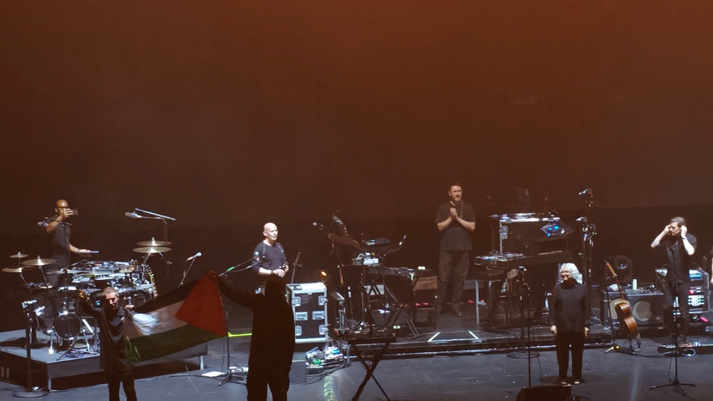 Massive Attack band members hold up a Palestinian flag during their Singapore concert (Reuters)