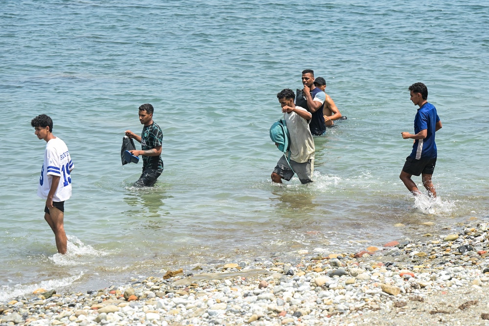 Migrants waddle in water, as they attempt to make their way past a group of Spanish soldiers (Reuters)
