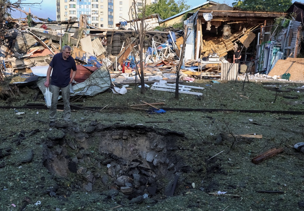 A resident looks at a crater at a site of a Russian missile strike, amid Russia's attack on Ukraine, in Kyiv region, Ukraine (Reuters)