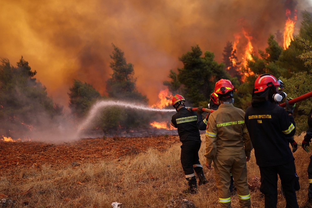 Firefighters battle a wildfire near the village Agia Paraskevi (Reuters)