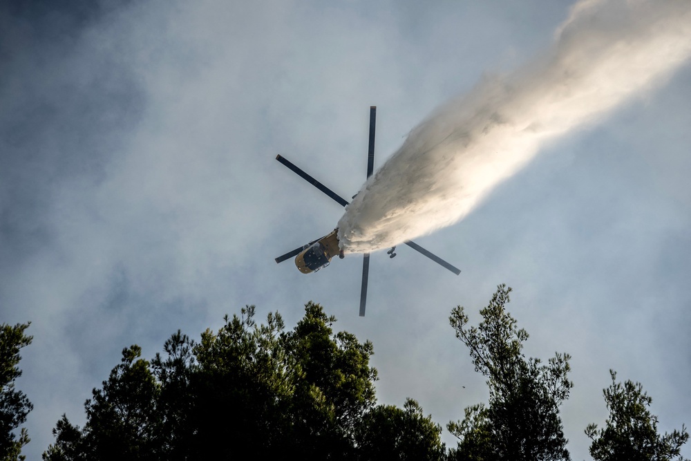 A firefighting helicopter drops water over a wildfire in the area of Porto Germeno (note: this picture does not depict the helicopter crash) (AFP/Getty)