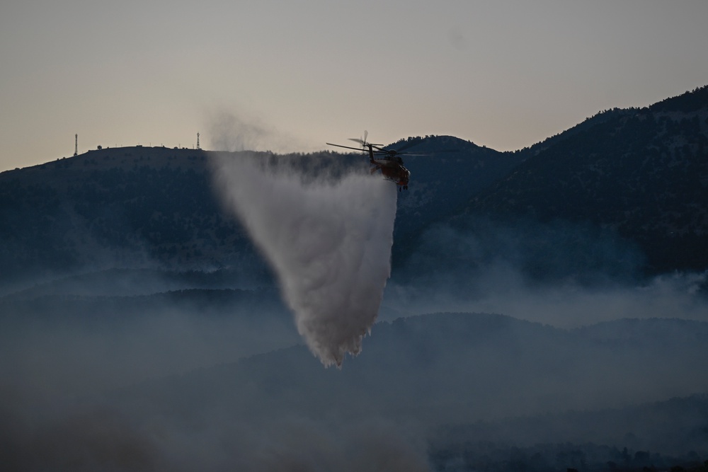 A firefighting helicopter drops water over a smoke-filled forest during a wildfire near Porto Germeno, northwest of Athens (Michael Varaklas/AP) (AP)