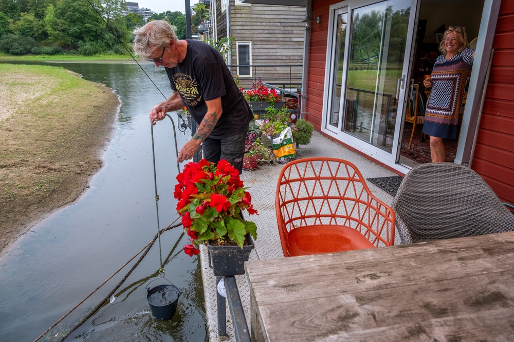 Houseboat owners pull up water for plants from the Waal river in Nijmegen (AP)
