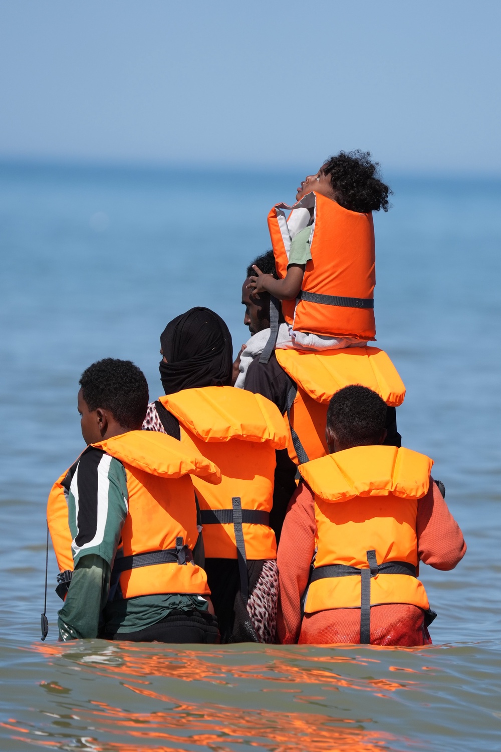 People thought to be migrants wade in the water as they attempt to board a small boat off the coast of Hardelot, France (Gareth Fuller/PA) (PA Wire)