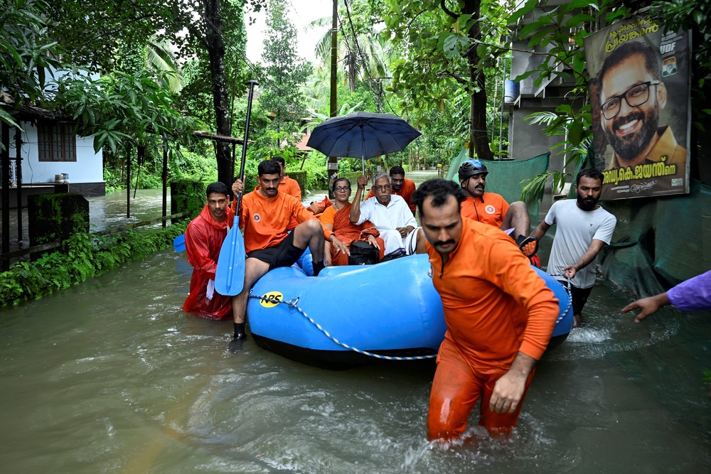 Rescue personnel move residents from a flooded neighbourhood following heavy rain in Kakkodi, Kerala, India (Reuters)