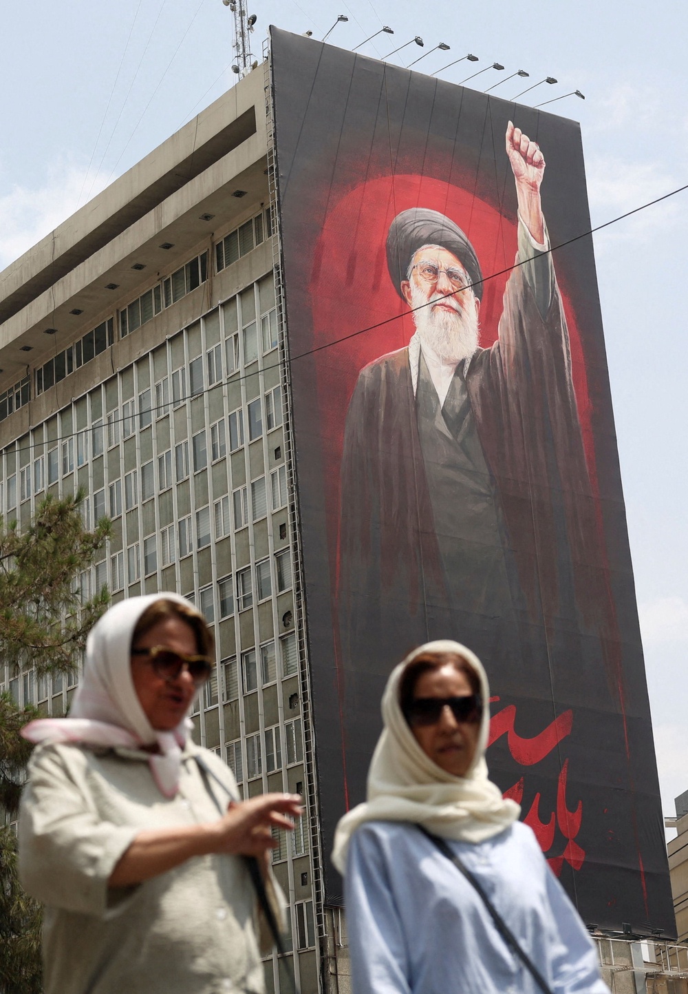 People walk near a billboard depicting Iran's late Supreme Leader Ayatollah Ali Khamenei, on a street in Tehran (Reuters)