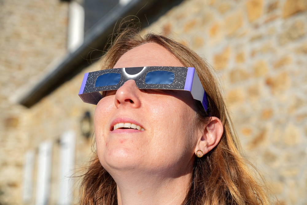 A woman is looking at the sun through a pair of special cardboard glasses designed to protect her eyes while watching the solar eclipse on August 12 in Saint-Pol-de-Leon, in the Finistere department of Brittany in western France, on August 1, 2026. (Photo by Nicolas Guyonnet / Hans Lucas / AFP via Getty Images) (AFP/Getty)
