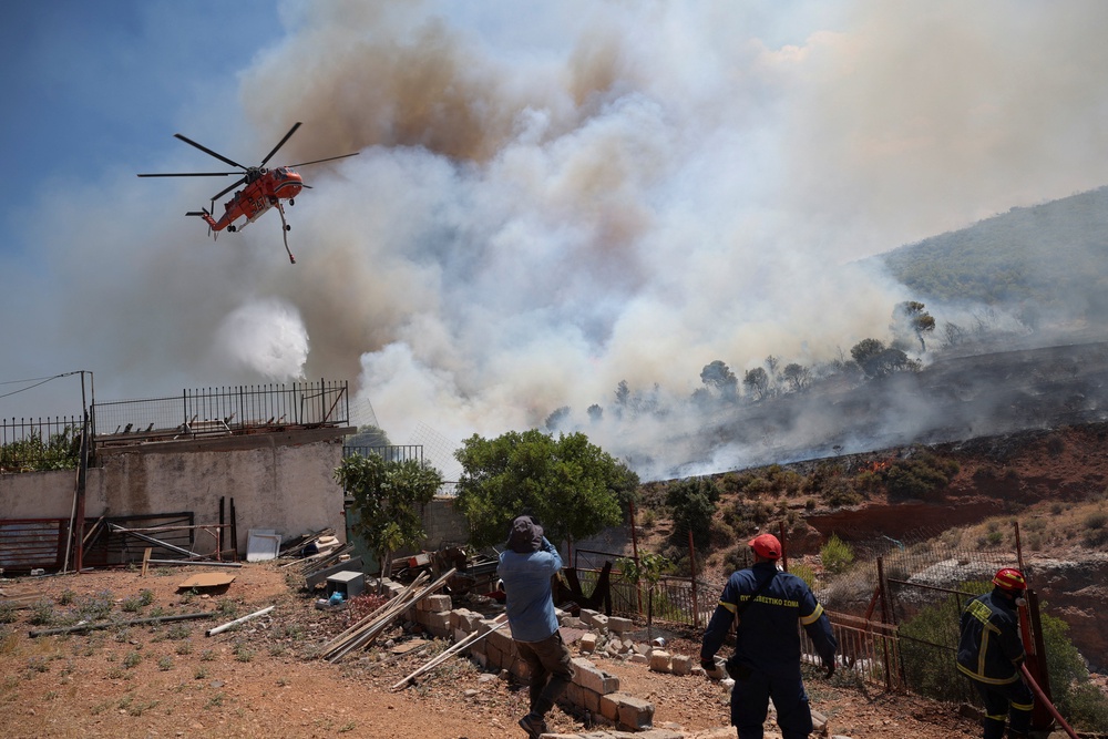 A firefighting helicopter operates as firefighters try to extinguish a wildfire in Vlychada, west of Athens, Greece, August 3, 2026 (Reuters)
