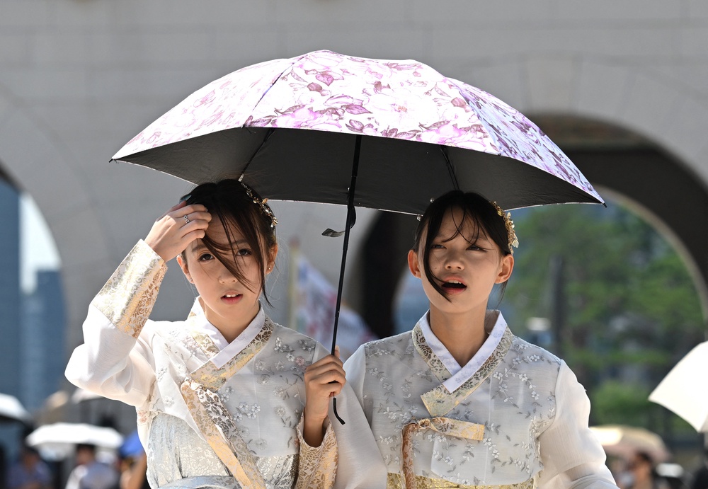 Tourists wearing traditional Hanbok dresses use a parasol to shield from the sun at the Gyeongbokgung Palace in Seoul (AFP/Getty)