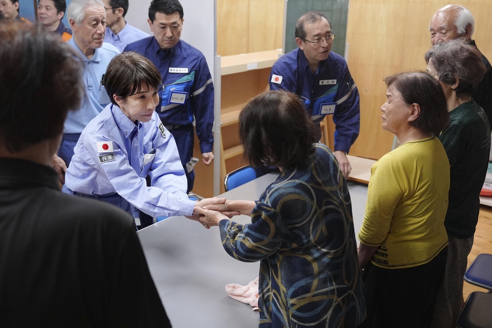 Japan's Prime Minister Sanae Takaichi, center left, greets evacuees as she visits an evacuation center in Hikawa, southern Japan (AP)
