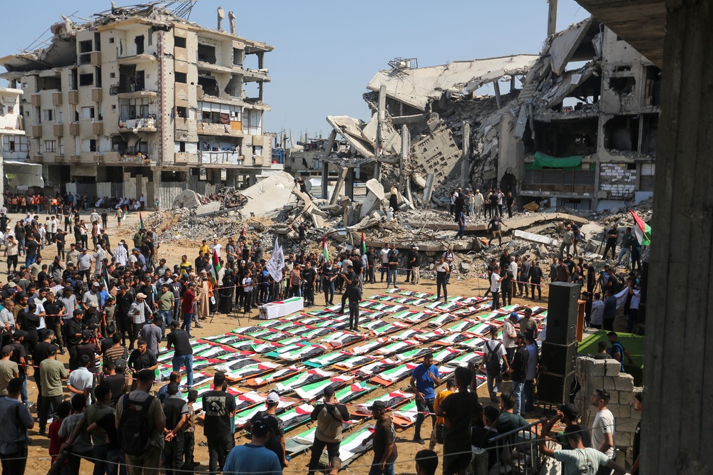 People attend a mass funeral for members of the Abu Sharia and Al-Hasayna families, whose remains were recently recovered from the rubble of their homes after an attack earlier in the war, on August 4 (Getty)